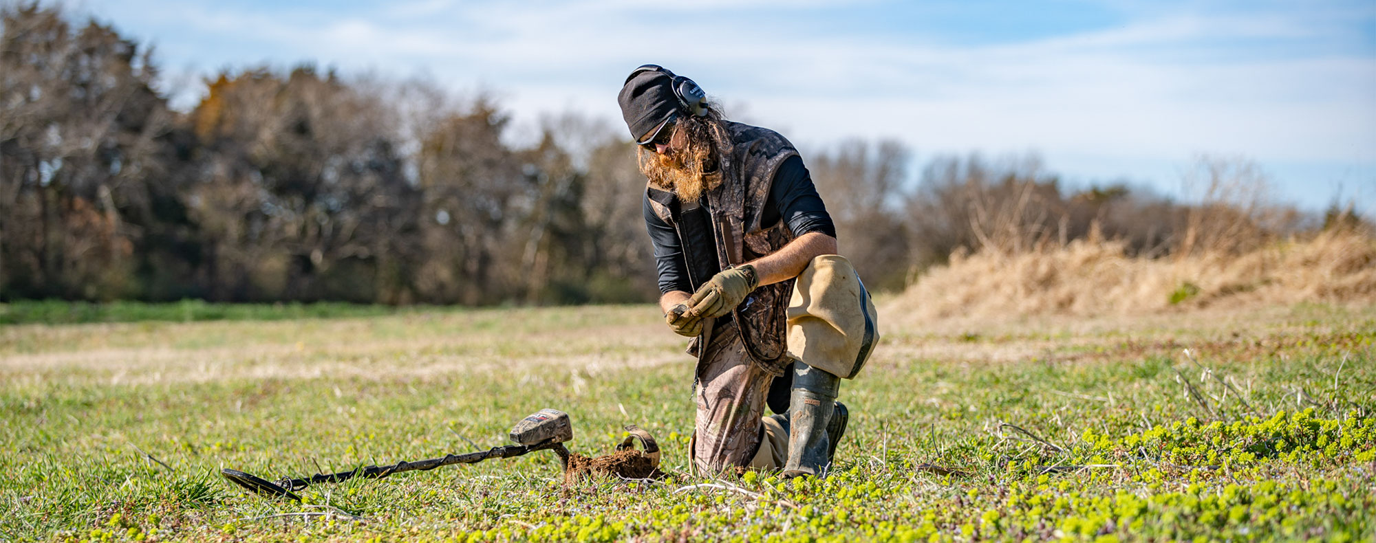 Jase Robertson in a field with a Garrett AT Max Metal Detector recovering artifacts